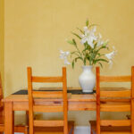 Table, lilies, yellow wall.