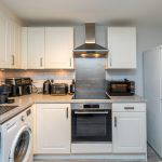 Kitchen with washing machine, oven, microwave, and fridge