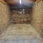 Garage with exposed brick walls and concrete flooring