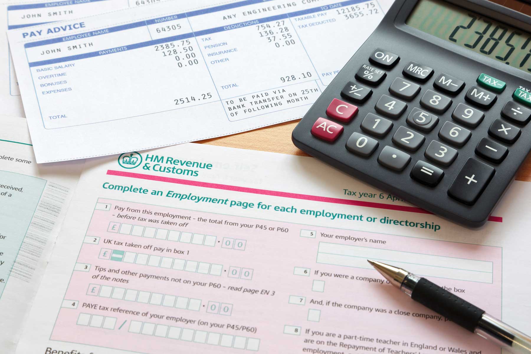 Photo of a UK self assessment tax return with calculator and payslips.